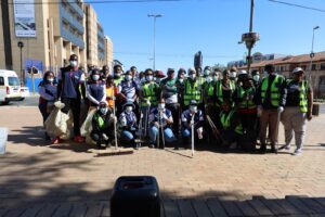 Volunteers in high-vis vests and masks pose with brooms and litter bags during the Mandela Day Randburg clean-up drive.